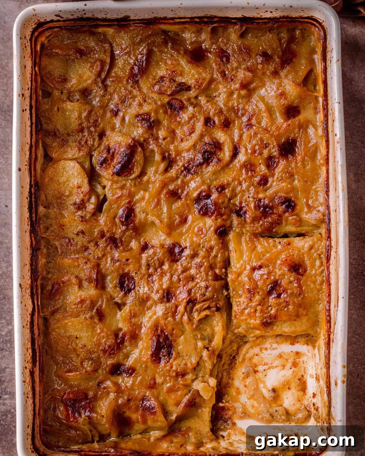 cheesy vegan scalloped potatoes in casserole pan with slice cut out