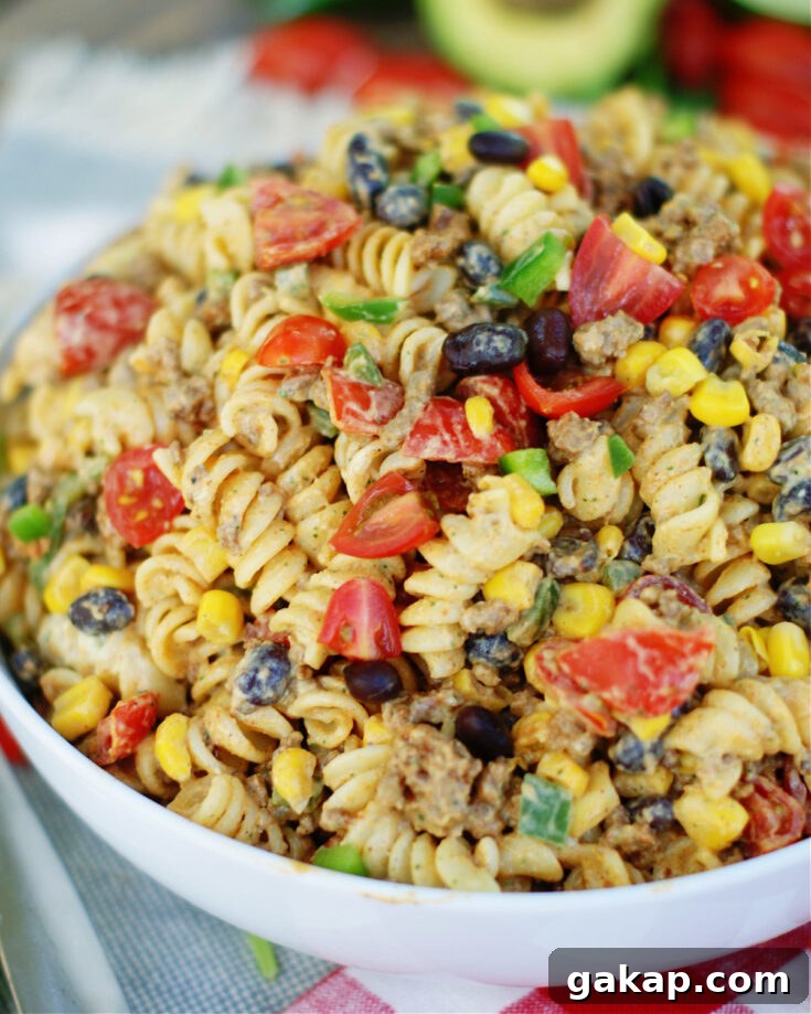Tex Mex Pasta Salad is loaded with seasoned ground beef, black beans, tomatoes, green onions, corn and jalapenos, then tossed in a cool, creamy avocado cilantro dressing with lime.