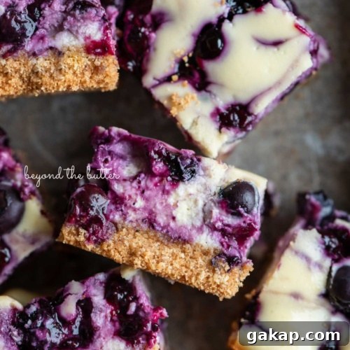 Sliced blueberry swirl cheesecake bars randomly placed in a vintage baking tin.