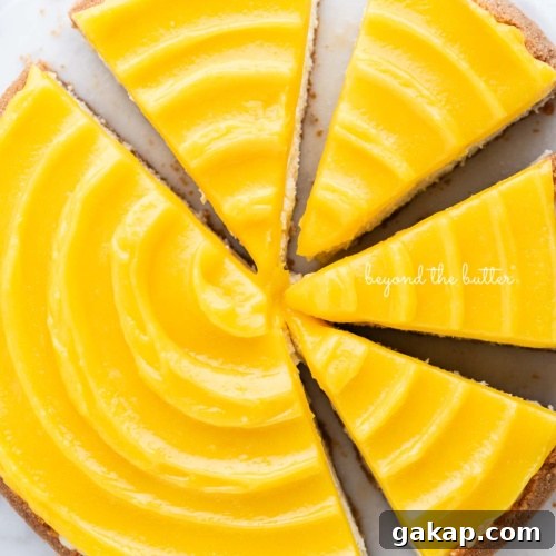 Lemon cheesecake topped with lemon curd cut into slices on a marble cake plate with white background.