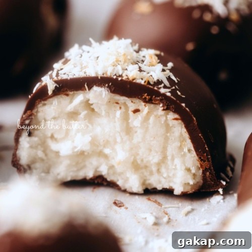 Chocolate dipped coconut buttercream eggs with center egg sliced in half to see the inside creamy texture on white background.
