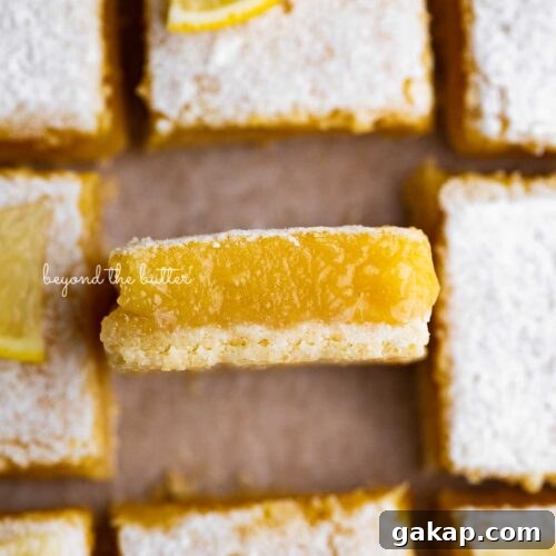 Sliced super easy lemon bars on parchment paper with the center lemon bar on its side.