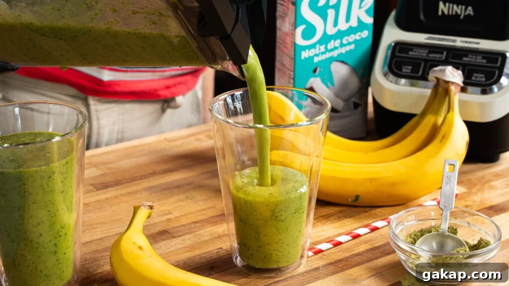 Tropical Green Island Smoothie — Ready in 5 Minutes 6 Pouring an island green tropical smoothie into a tall glass.