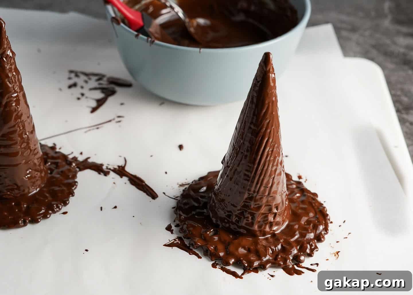 Chocolate witch hats made of ice cream cones and pizelles on parchment paper