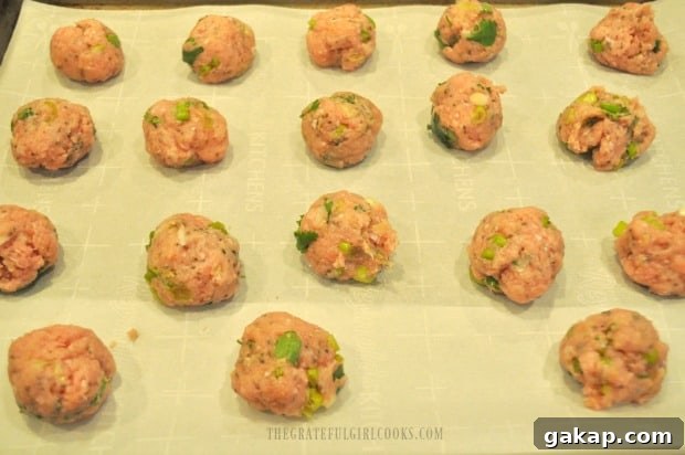 The Thai turkey meatballs on parchment paper lined baking sheet before baking.