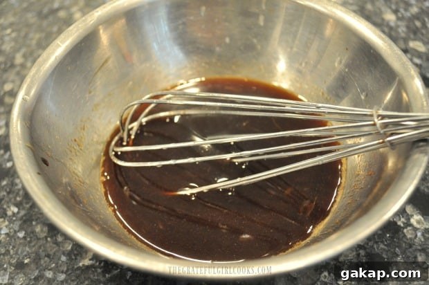 The ingredients for Asian sauce to coat the Thai turkey meatballs after baking is whisked in bowl.