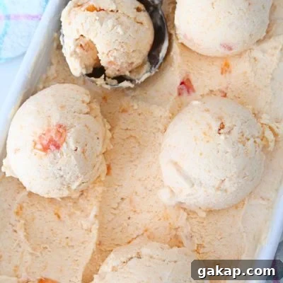 A few balls of peach ice cream in an ice cream container