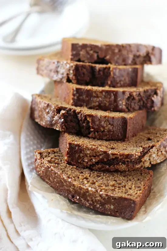 Slices of Healthy Maple Gingerbread on a white platter with a napkin to the side.