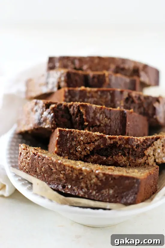 Stacked slices of Healthy Maple Gingerbread Loaf on a white dish.