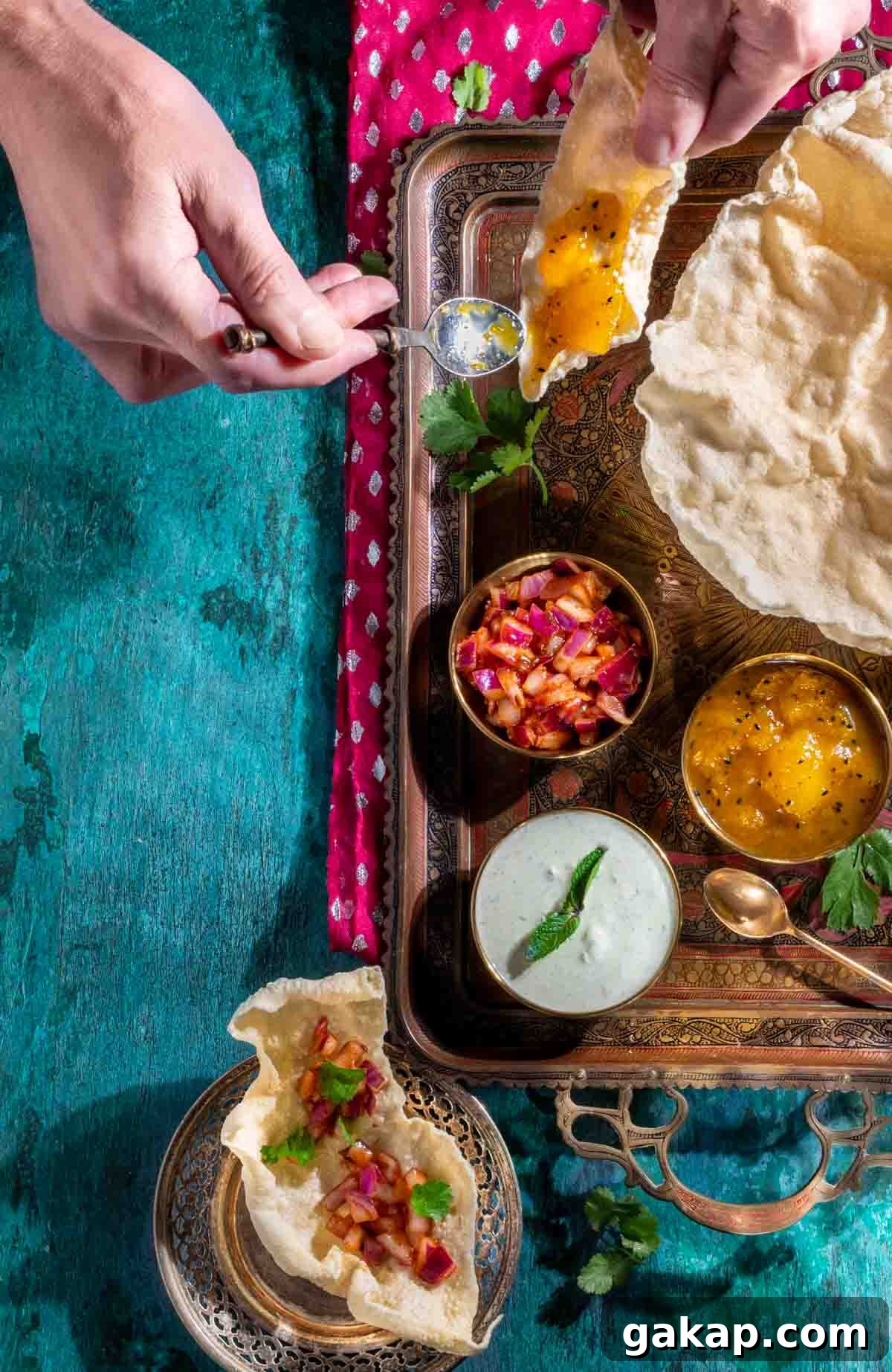 Various dips for poppadoms in snall bowls on a gold tray, surrounded by poppadoms.
