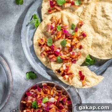 Indian onion chutney spread over poppadoms on a grey background.