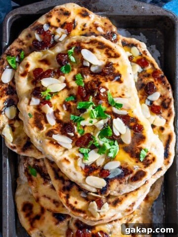 A pile of Peshwari naans in a baking dish on a blue background.
