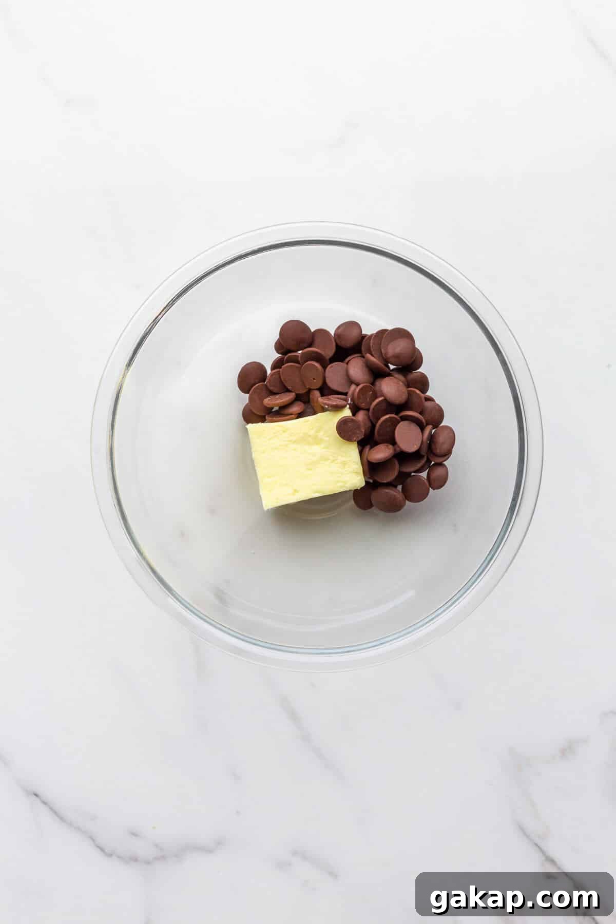 A glass bowl with chocolate and butter to be melted together to make chocolate frosting.