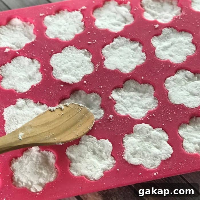Tea Tree Acne Facial Tabs — Lush-Inspired Formula for Clear Skin 7 pressing mixture for tea tree essential oil facial steamer tabs into flower shaped silicone molds with wooden spoon