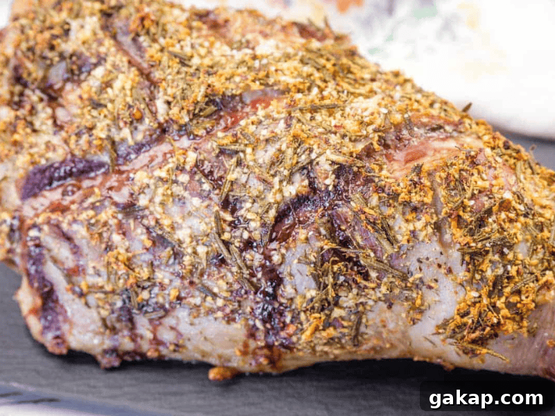 13 Classic Vintage Recipes for Cozy Fall Cooking 3 Close-up of a roasted lamb leg covered with a crust of herbs and spices, resting on a dark surface.