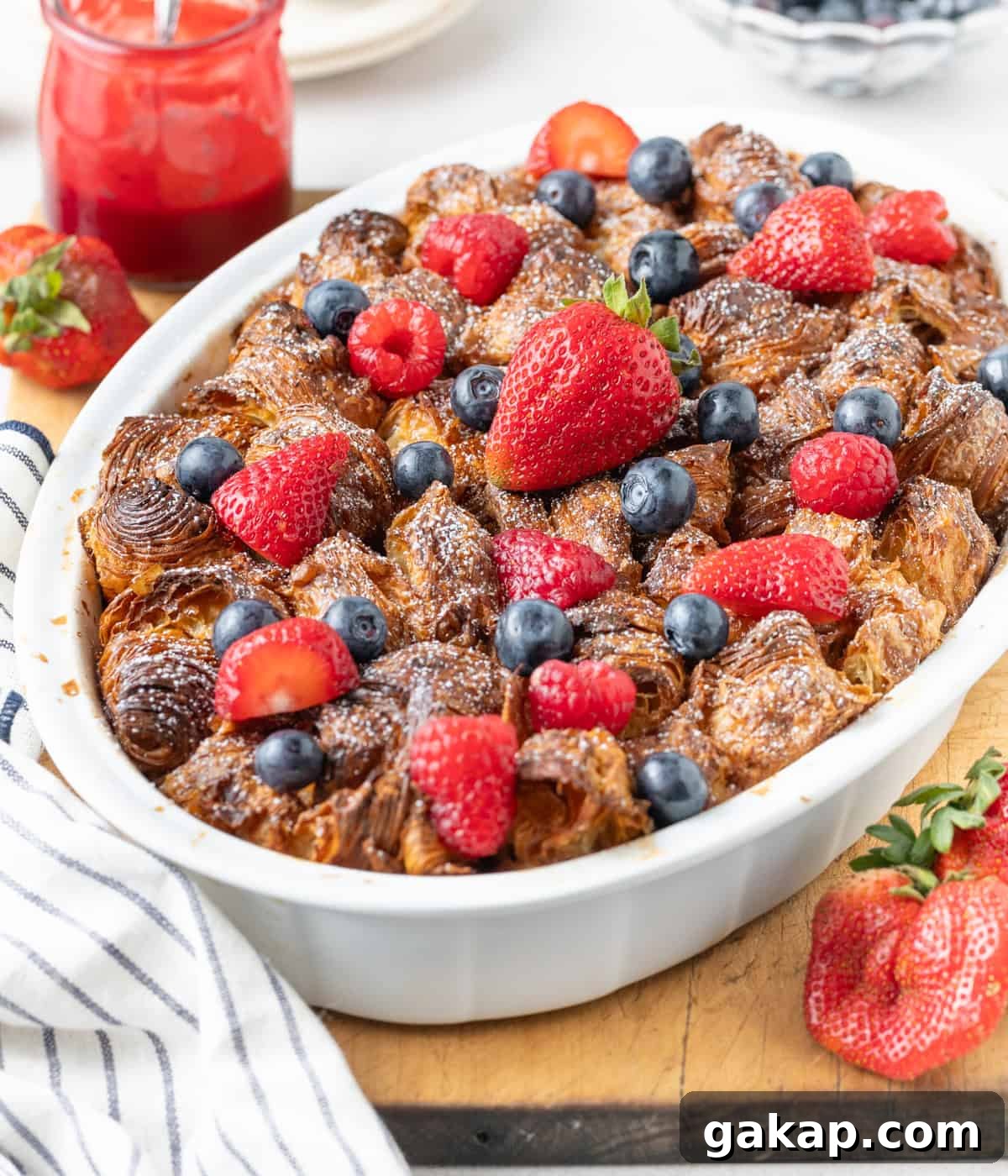 Decadent Croissant French Toast Casserole Recipe 7 45 degrees view on the dish topped with fresh berries and icing sugar.