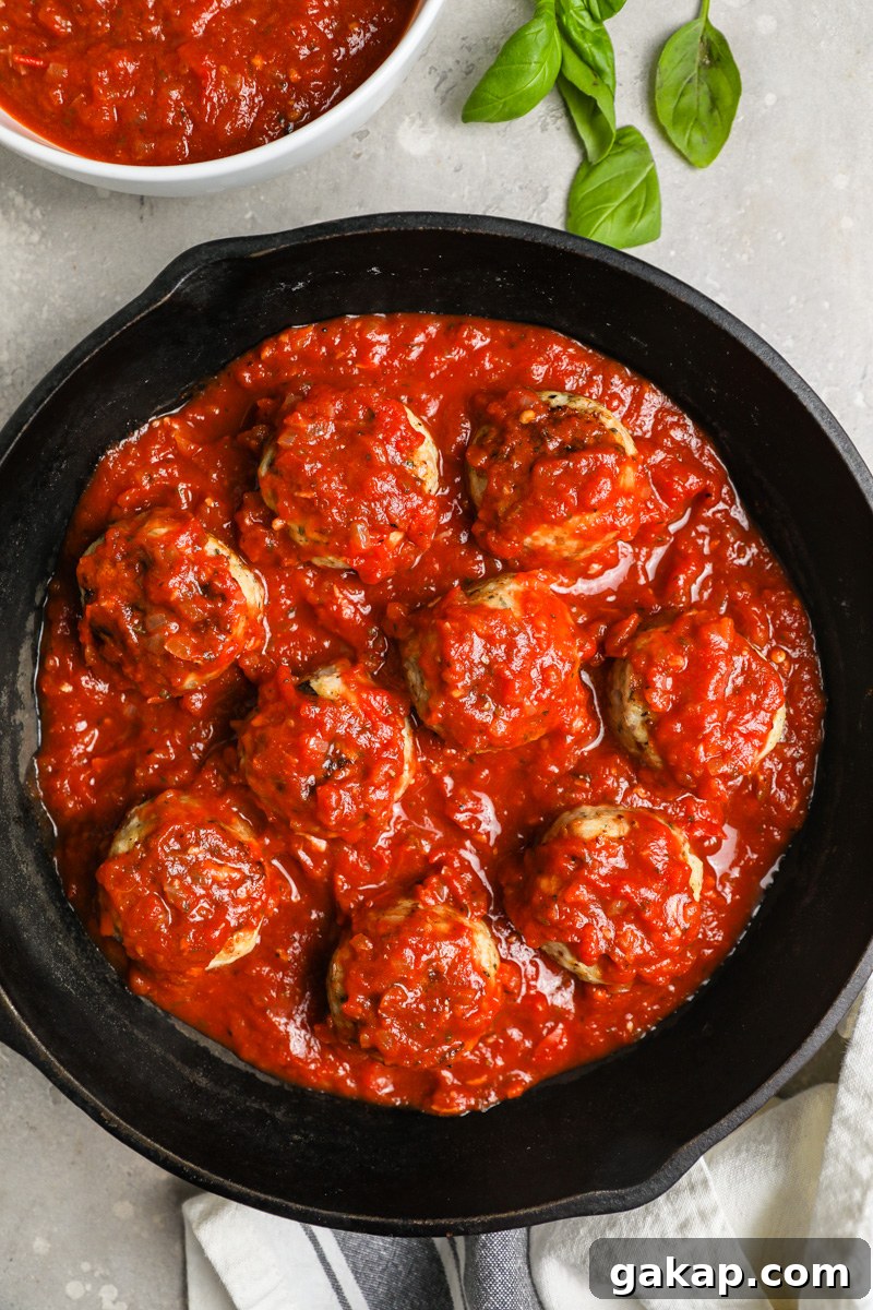 A large skillet filled with Italian chicken meatballs tossed in marinara sauce