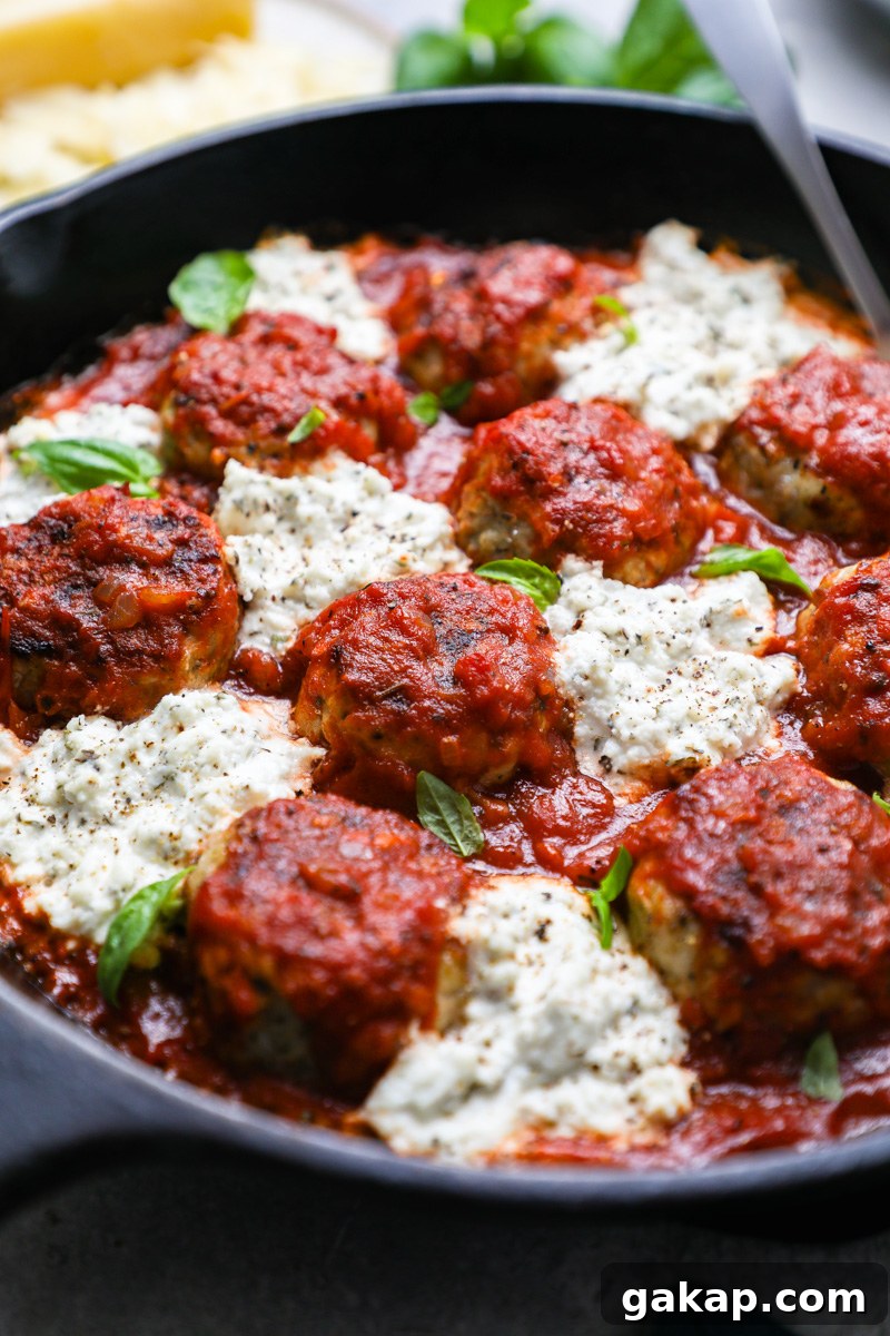 Italian chicken meatballs with herbed ricotta sitting in a large baking dish topped with fresh basil