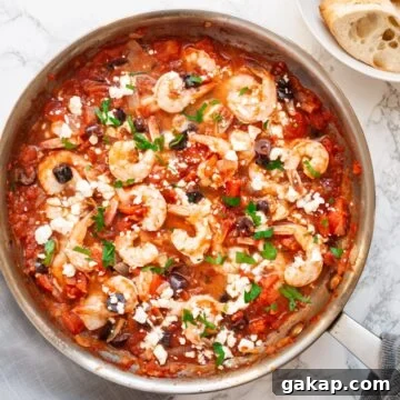 A top down view of Greek shrimp with tomatoes and feta cheese in a skillet.