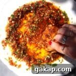 Hand swirling bread through sundried tomato dipping oil.