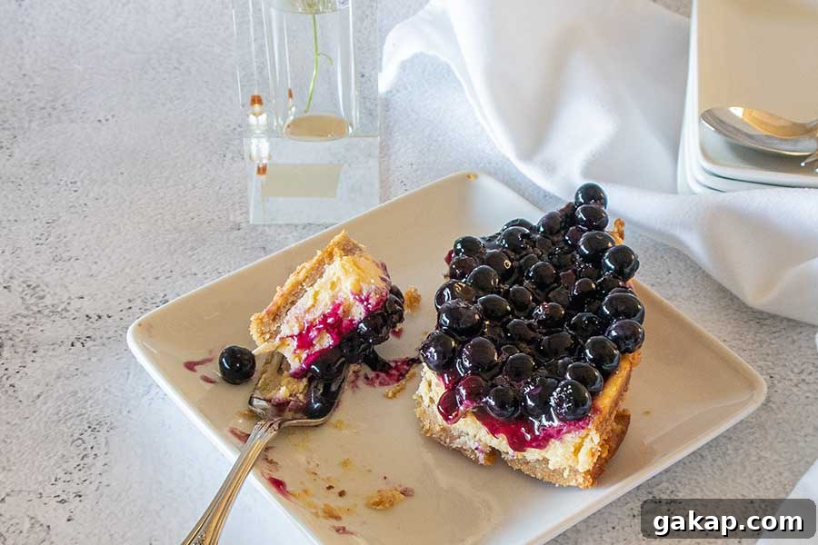 fork cutting a piece of 3 layer blueberry key lime cake on a dessert platter