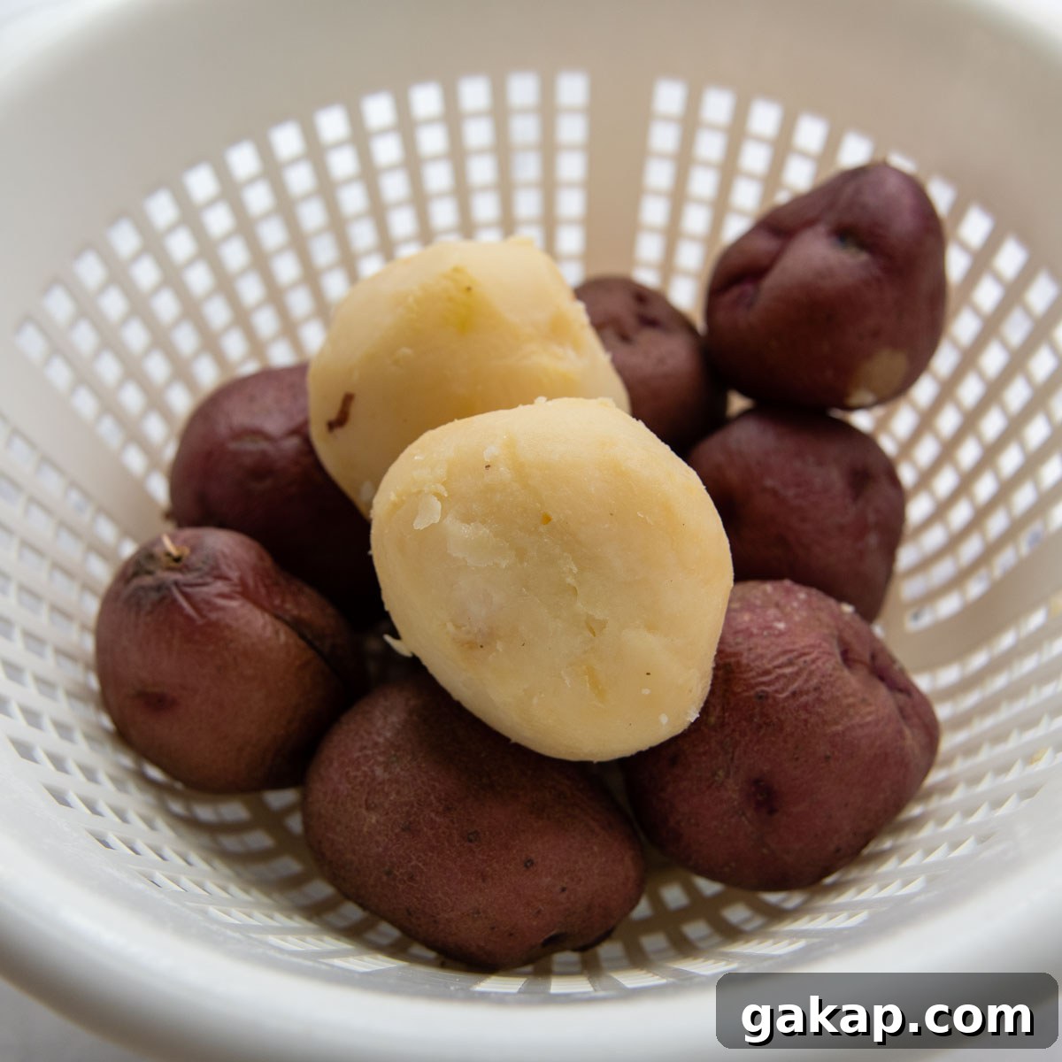 boiled potatoes in a colander with one peeled.