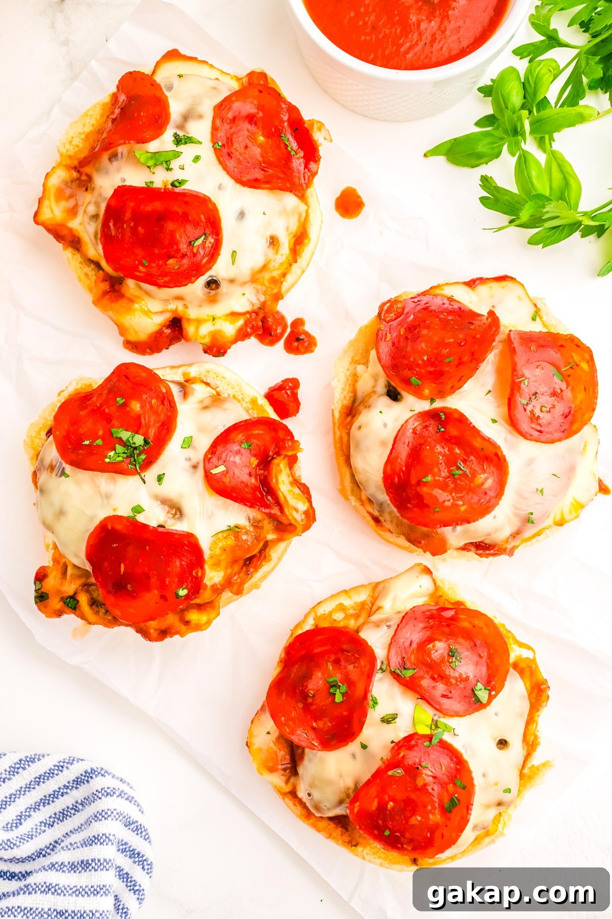 Four pizza burgers without the top bun on them so you can see the beef patty, sauce, melted mozzarella cheese, and pepperoni.