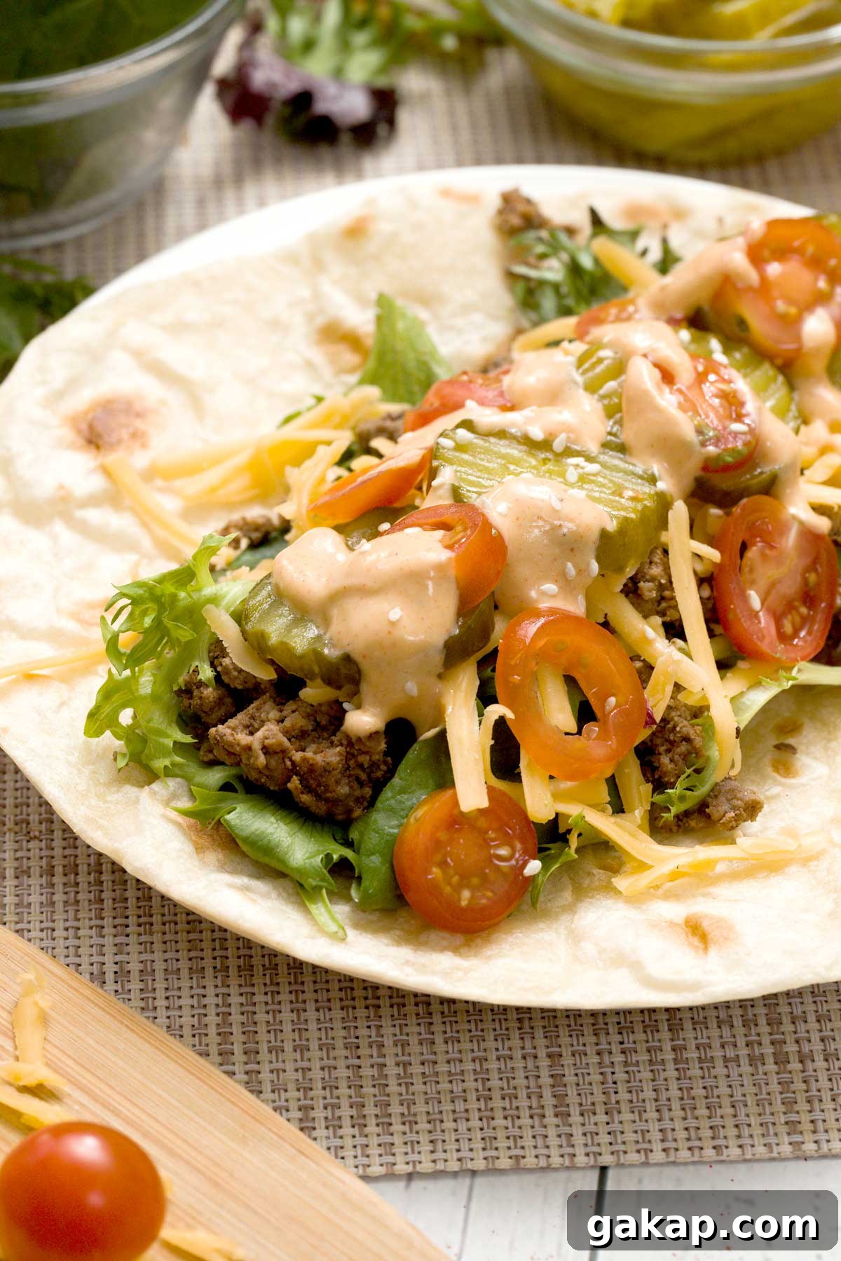 Copycat McDonald's Big Mac Wrap with Signature Sauce Recipe 4 An open big mac wrap on a tortilla with shredded cheese and McDonald's sauce.