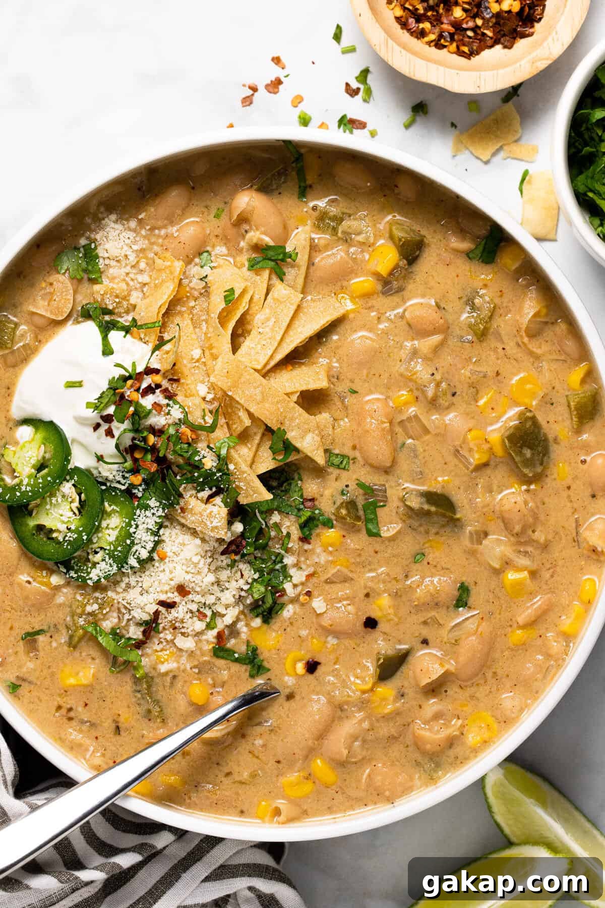 Large white bowl filled with white bean chili topped with tortilla strips