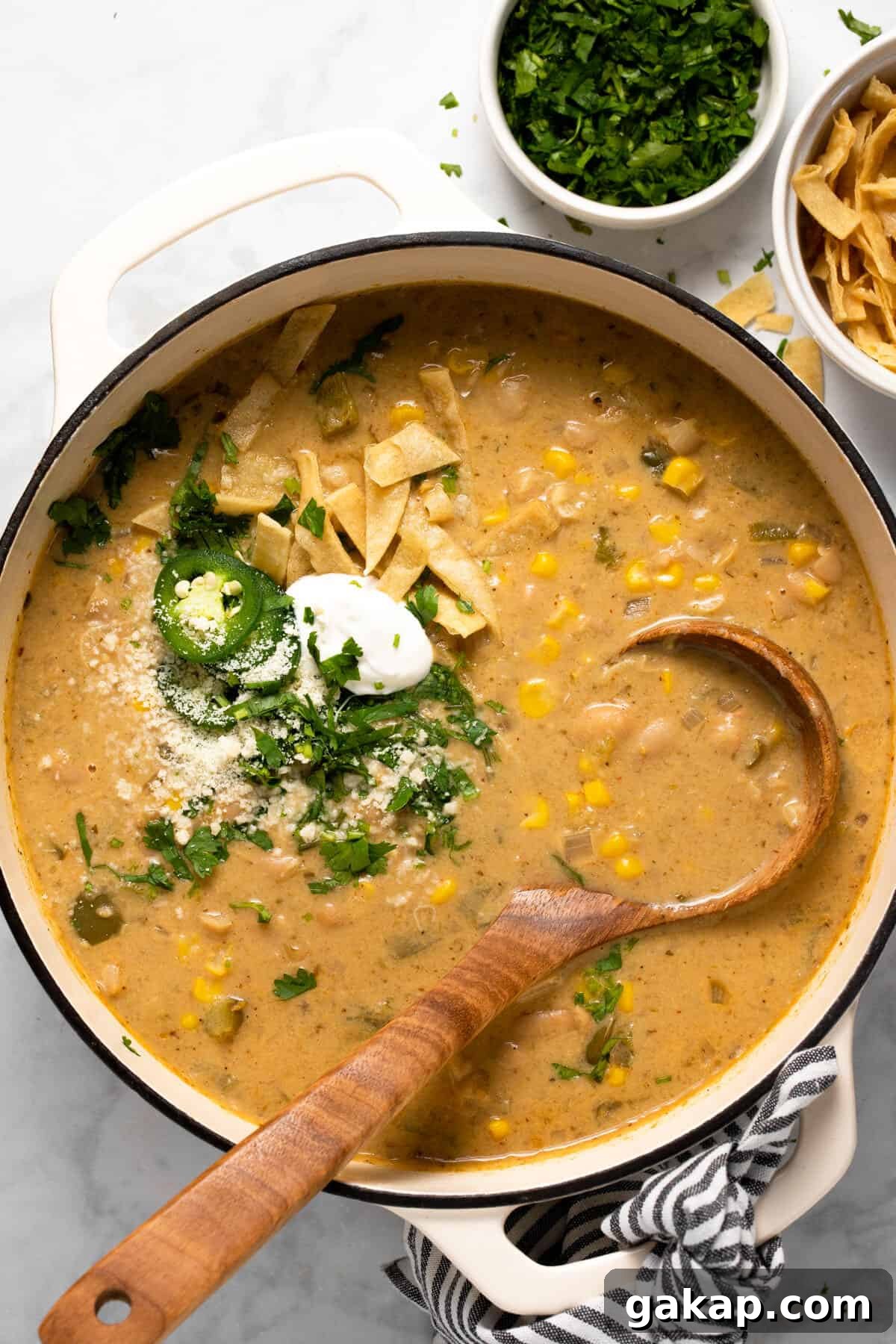 Large white pot filled with white bean chili topped with tortilla strips