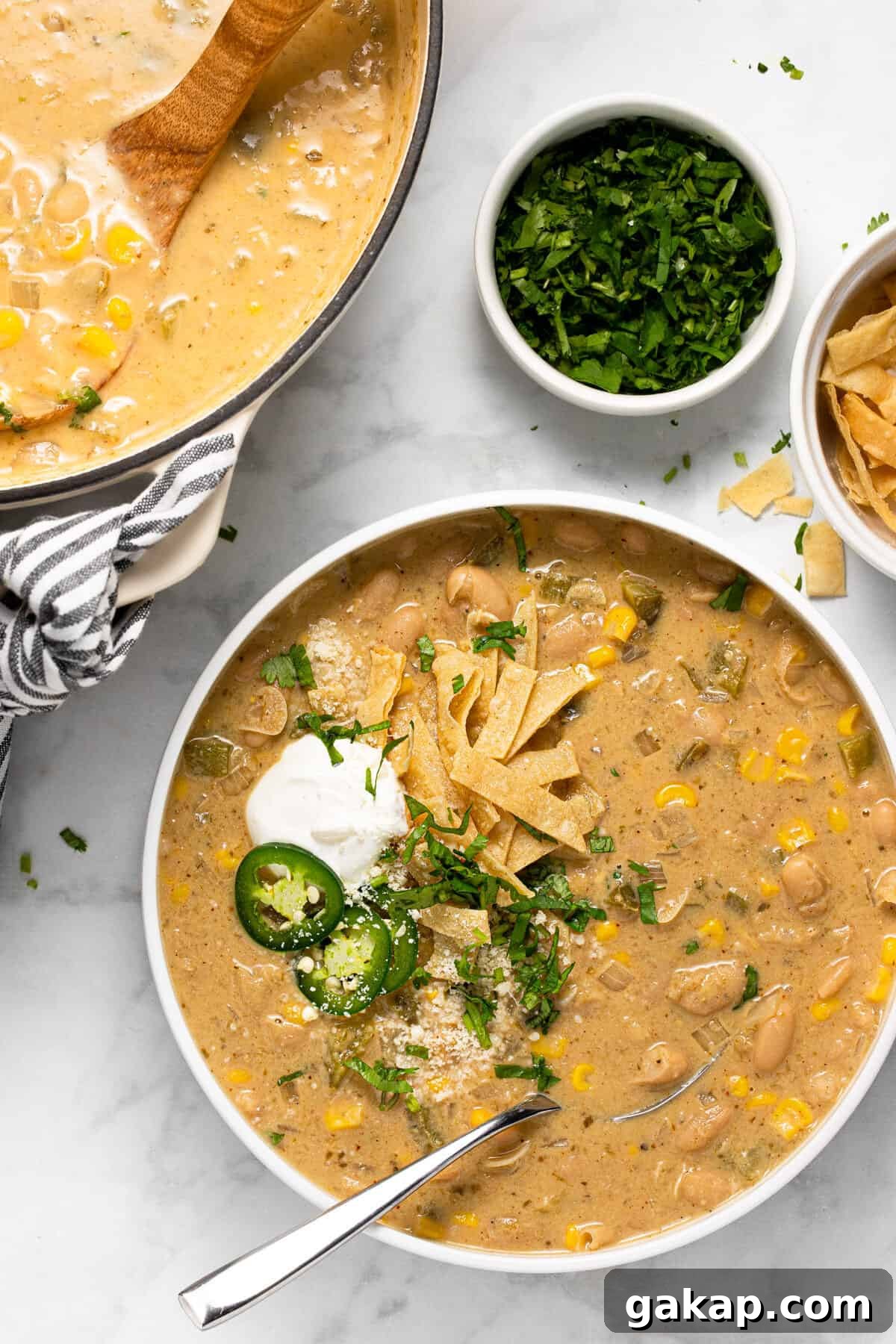 Large white bowl filled with white bean chili topped with tortilla strips