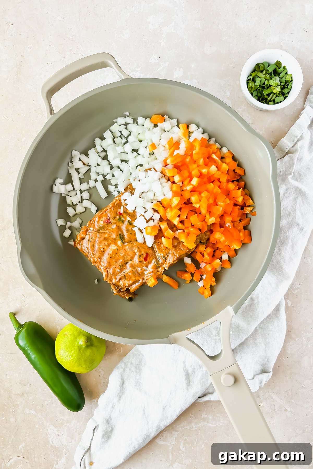 raw ground chicken, diced onion, and diced peppers in tan skillet.