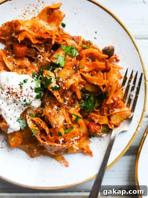 Creamy Roasted Red Pepper & Tomato Pasta Recipe 9 Pappardelle pasta with mushroom ragu, topped with cheese and herbs on a plate.