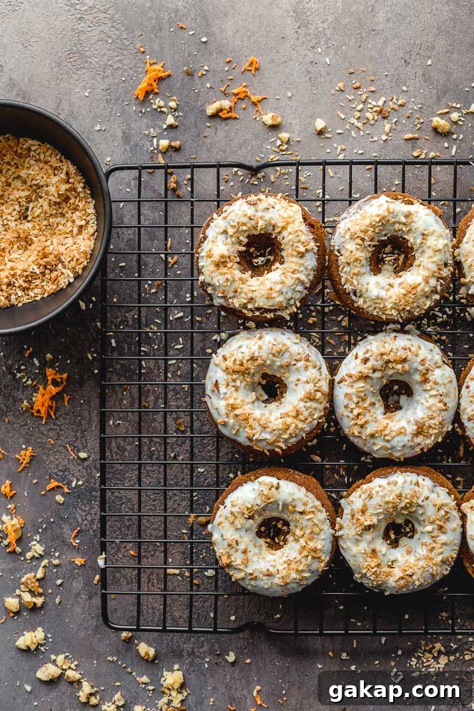 Gluten-Free Carrot Cake Donuts: Soft Spiced Donut Recipe 3 Carrot donuts on a wire rack topped with white chocolate and coconut.