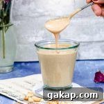 Scooping some peanut sauce out of a glass cup