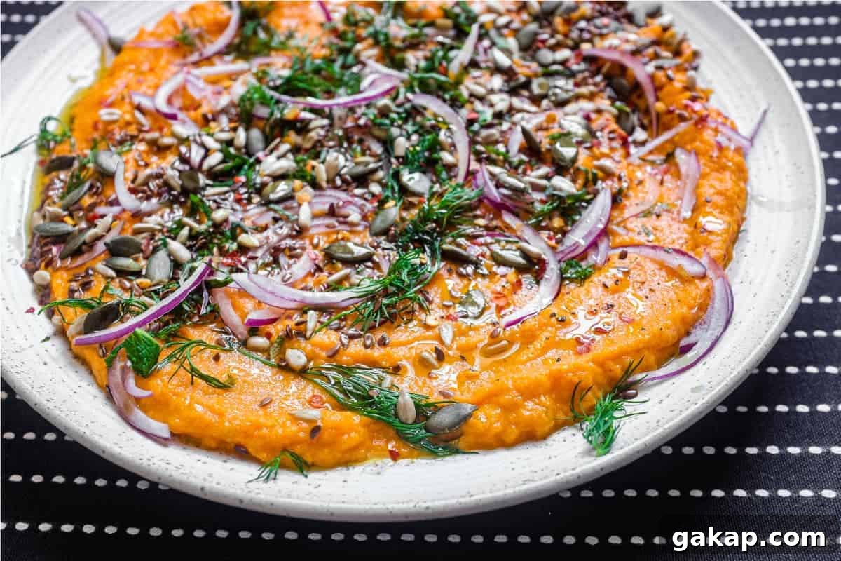 A platter of Turkish carrot salad scattered with herbs, seeds and red onion