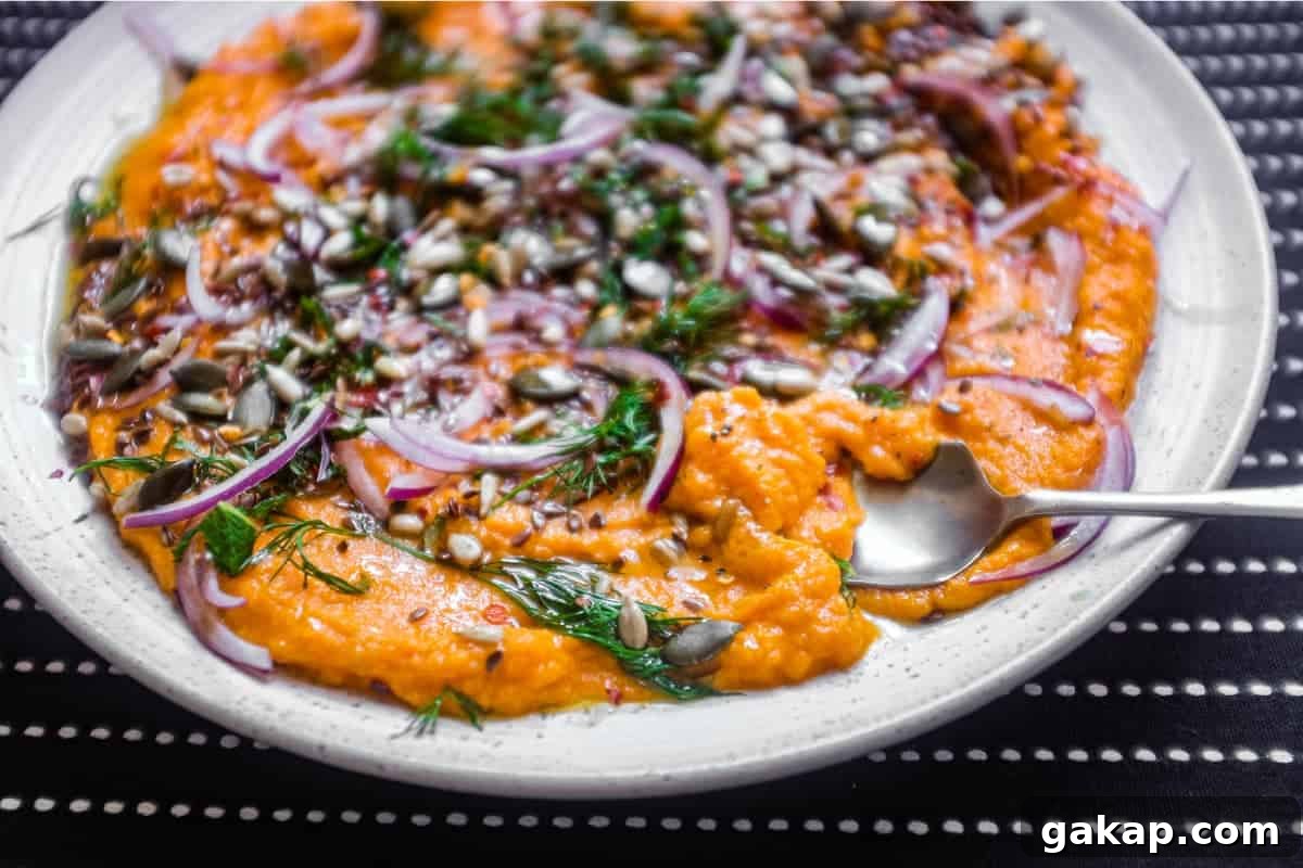 A platter of Turkish carrot salad scattered with herbs, seeds and red onion