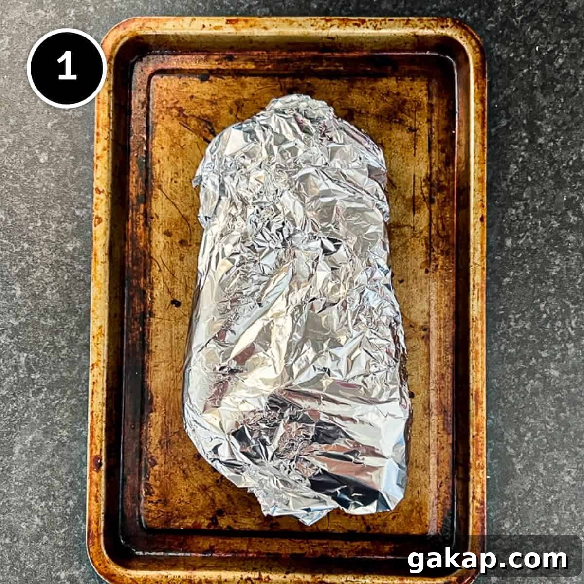 Carrots and garlic wrapped in foil on a baking sheet