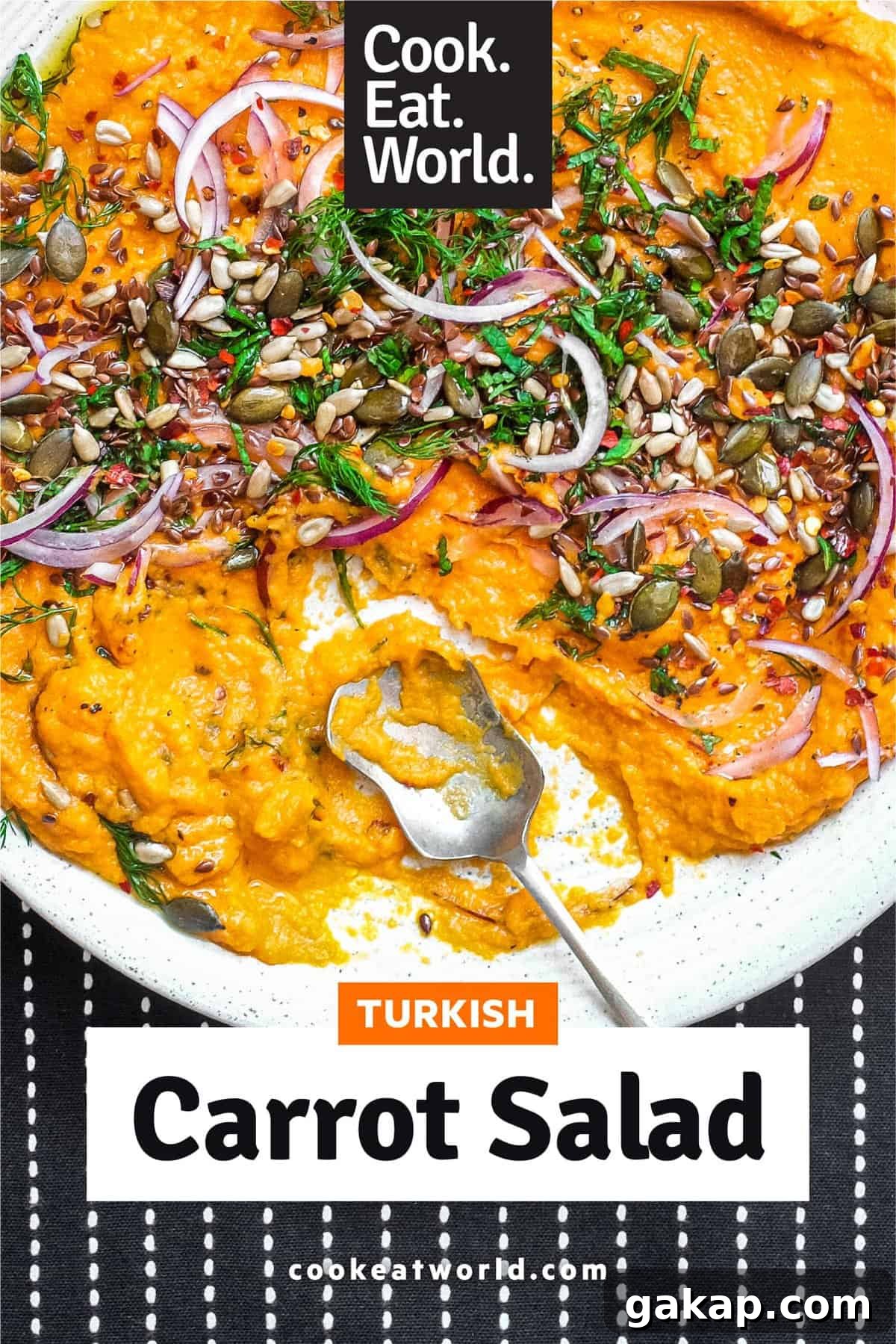 A platter of Turkish carrot salad scattered with herbs, seeds and red onion