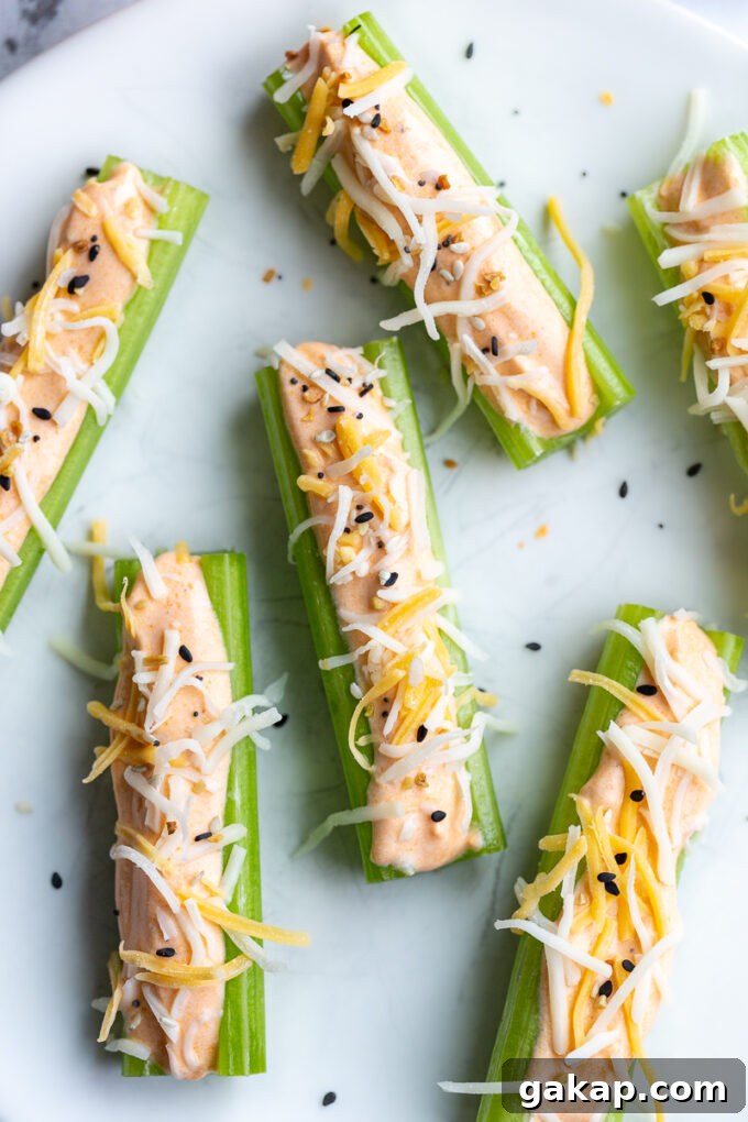 celery sticks on a plate topped with whipped buffalo cottage cheese and topped with shredded mexican cheese