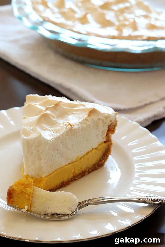 A slice of homemade lemon meringue pie on a white plate.