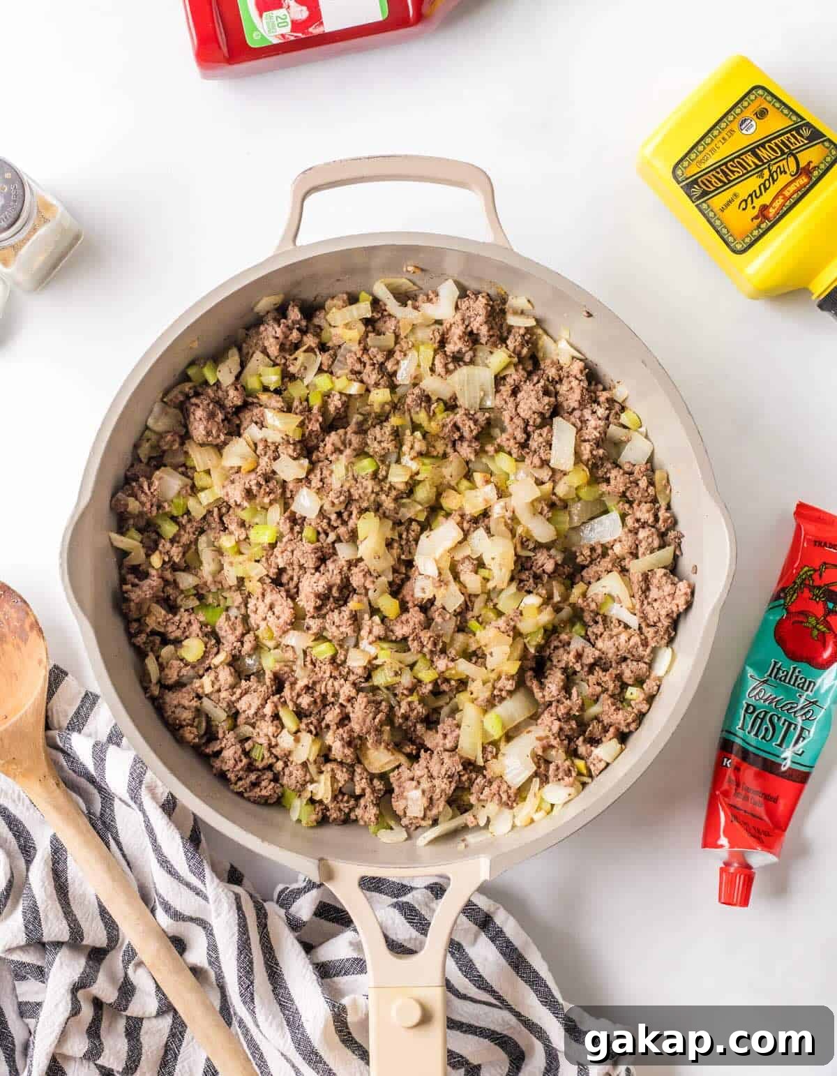 Cooked ground beef in a skillet with celery and onion.
