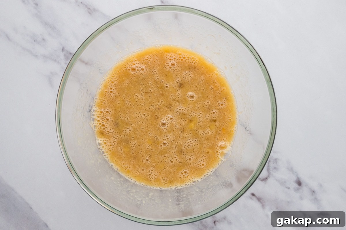 Mashed bananas and wet ingredients in a large mixing bowl for almond flour banana bread.
