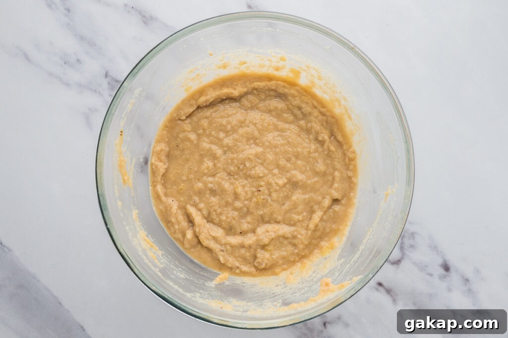 Banana bread batter being mixed in a bowl with almond flour and dry ingredients added.