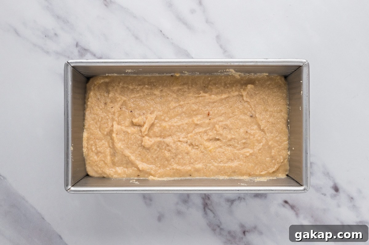 Almond flour banana bread batter poured into a parchment-lined loaf pan ready for baking.