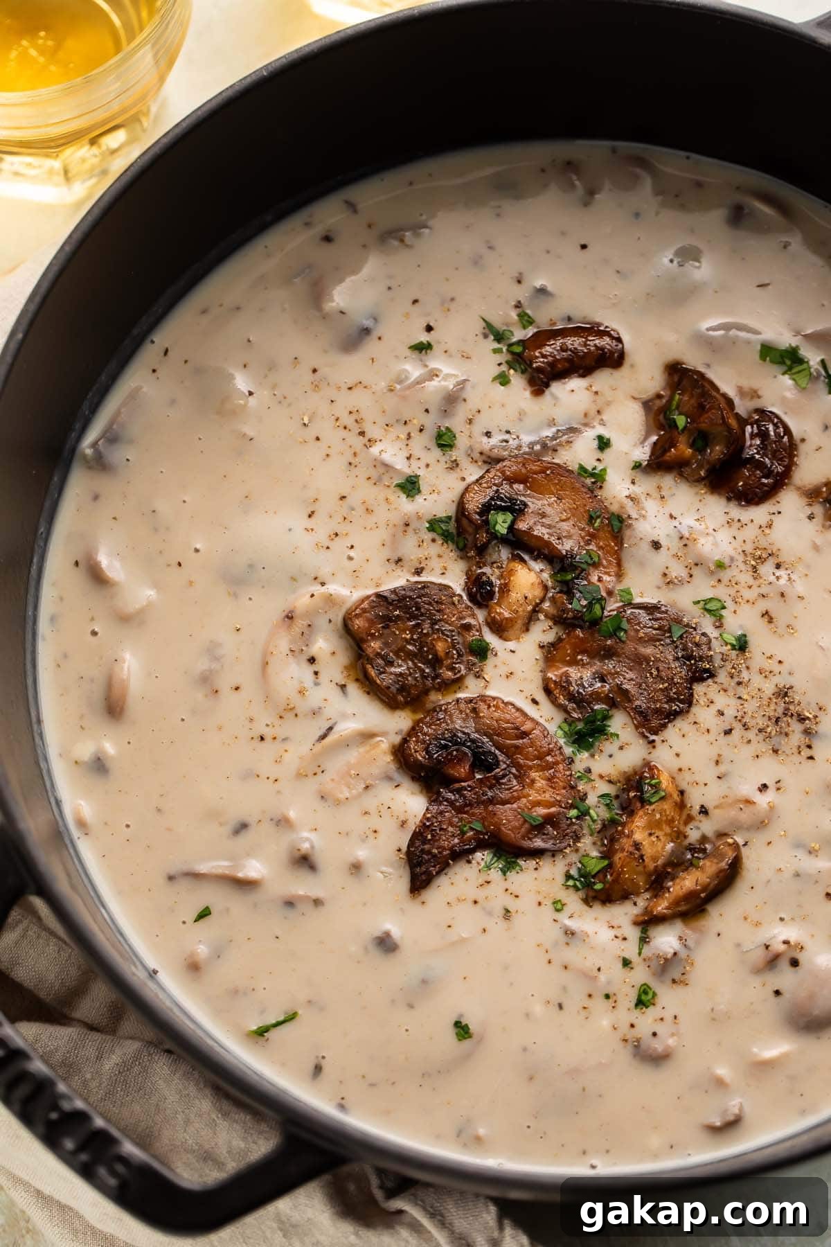 A large pot of creamy gluten free cream of mushroom soup with sautéed mushrooms garnishing the top.