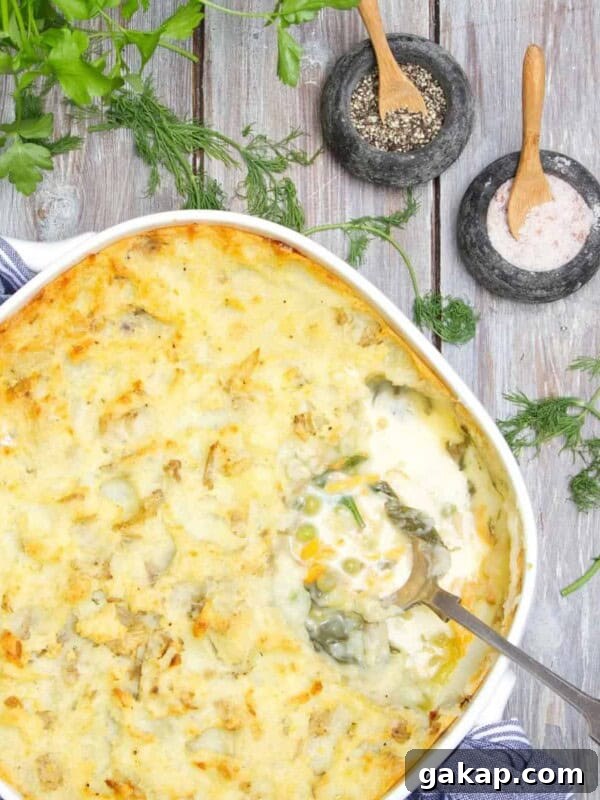 Fish pie being served with silver spoon on a wooden table.
