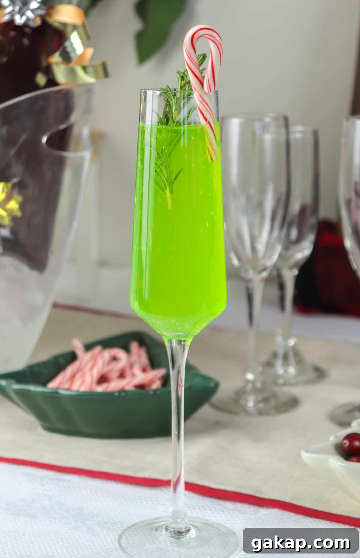 Green Grinch Mimosa Cocktail Recipe for Holiday Brunch 4 Grinch mimosa on table with candy cane.