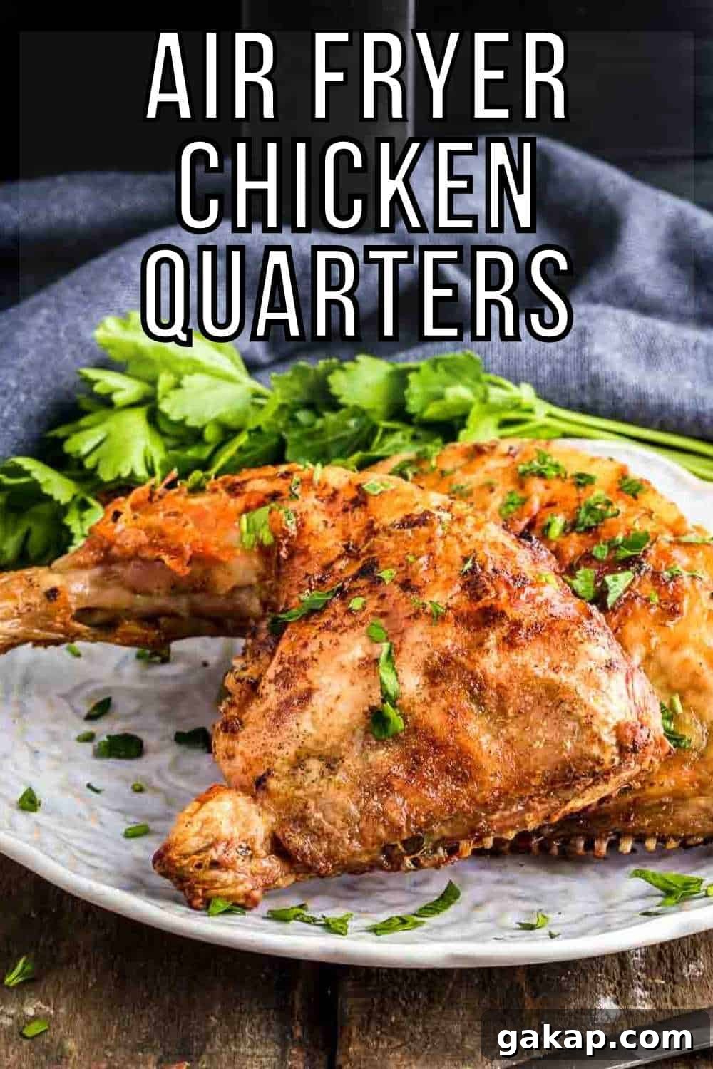 Crispy Air Fryer Chicken Leg Quarters with Garlic Herb Rub 2 Side shot of two chicken quarters garnished with herbs on a white plate on a wooden table and a blue cloth in the background.