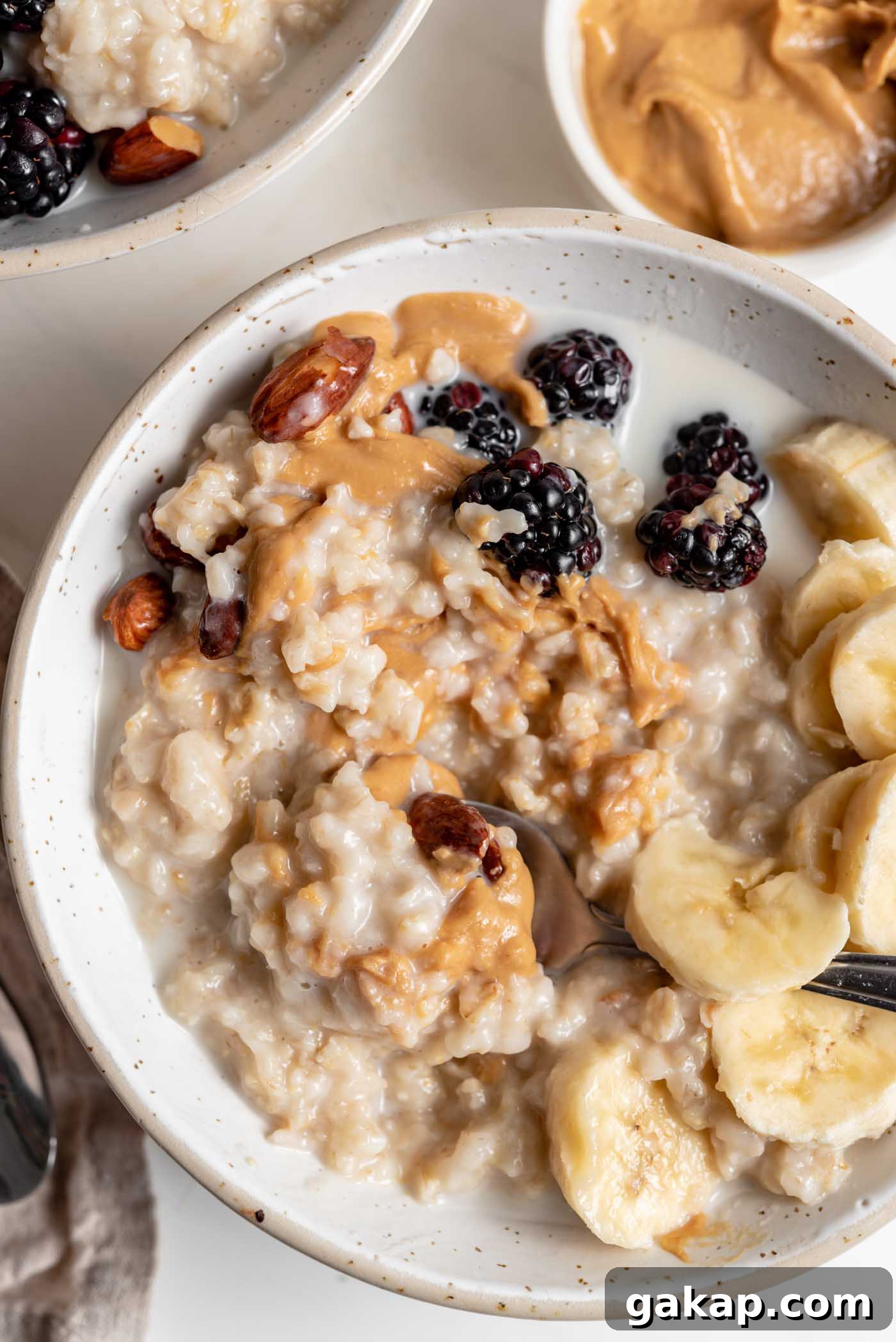 Overhead image of a bowl of oatmeal topped with peanut butter, banana and berries.